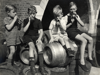 350215 Afbeelding van vier jongetjes met een flesje Joy limonade op een stapel vaten op de werf bij Groothandel in ...
